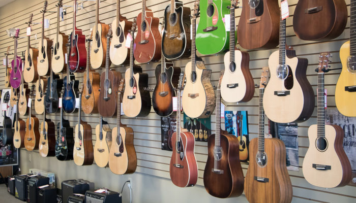 Acoustic guitars of different colors displayed on a wall.