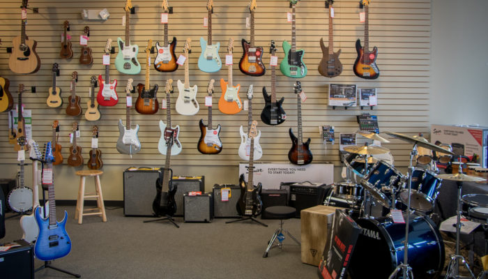 Electric guitars displayed on a wall with amplifiers beneath them.