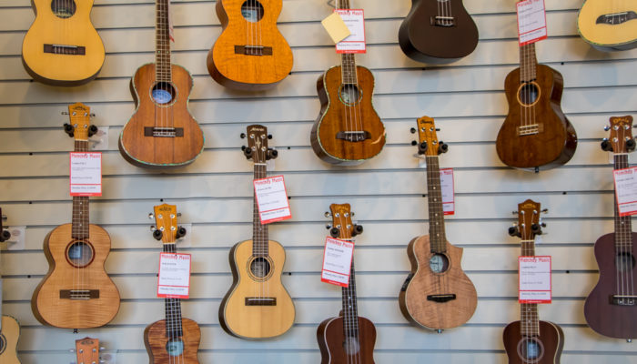 Wall display of ukuleles with varied wood finishes.