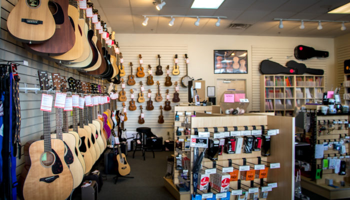 Acoustic and electric guitars by Yamaha, Ibanez and Fender hanging on wall.