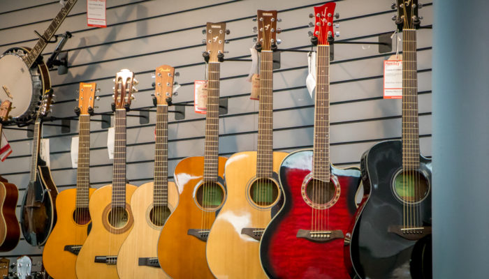 Six acoustic guitars hung on wall.