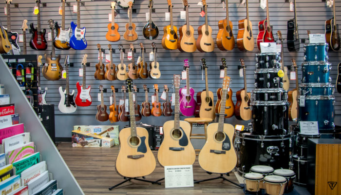 Large selection guitars displayed on floor stand and wall.