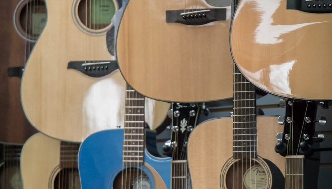 Closeup of the bodies of seven acoustic guitars.