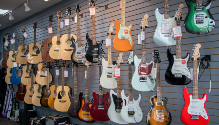 Electric and acoustic guitars on wall display.