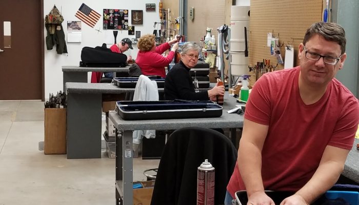 Four repair technicians working on orchestral instruments.