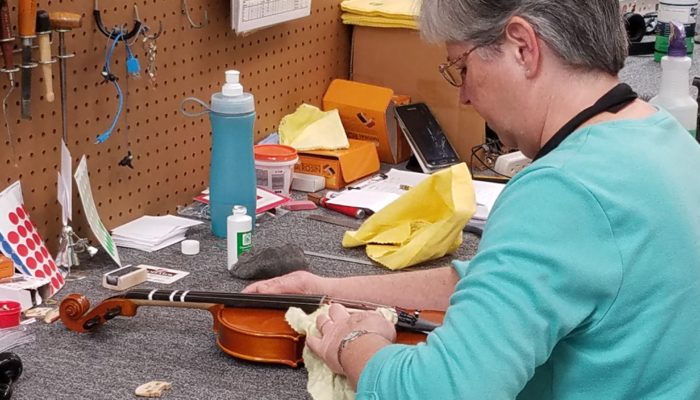 Repair technician cleaning a violin.