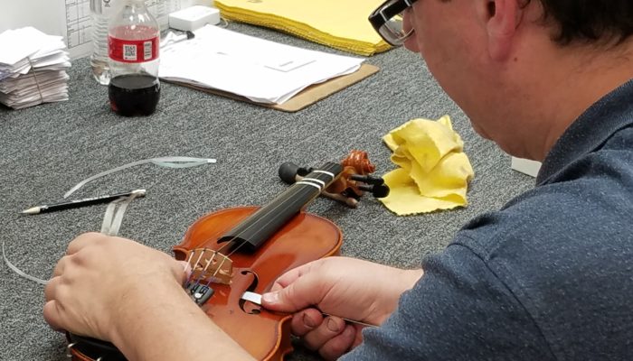 Instrument repair technician fixing the sound post on a violin.