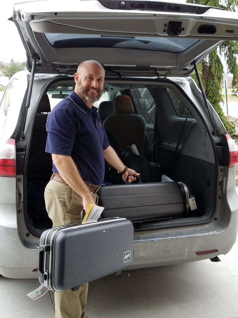 Man holding saxophone outside of a van.