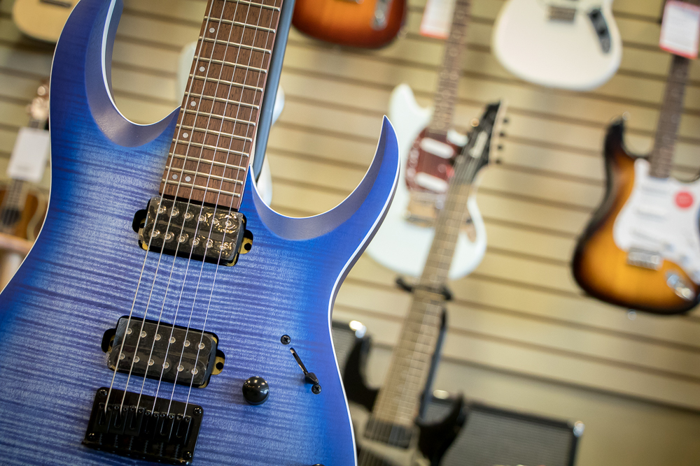 Blue electric guitar with other electric guitars hung behind it.