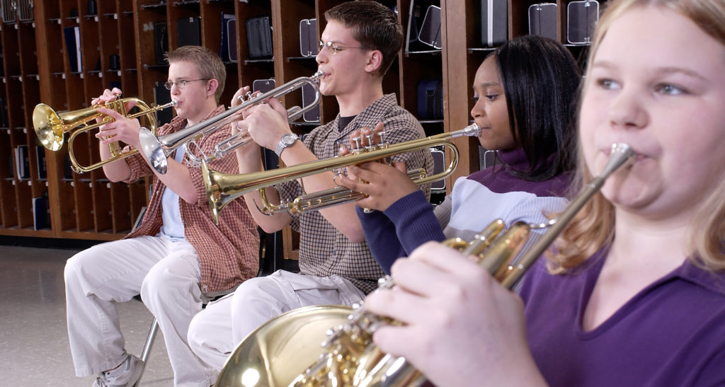 Four students playing band instruments