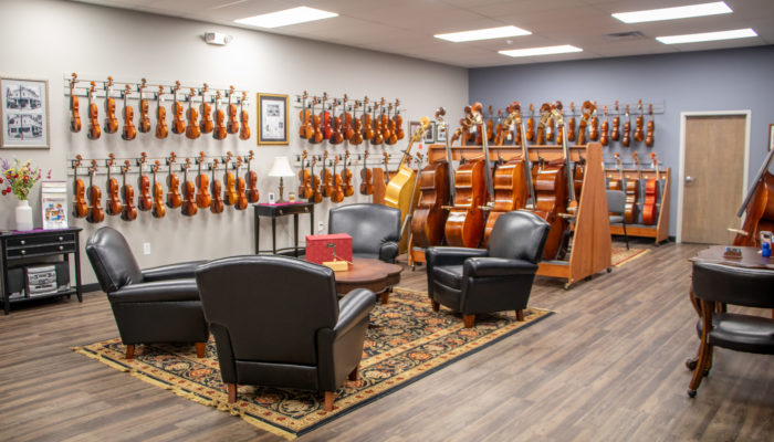 Large room with seating area and selection of cellos, violins and violas.