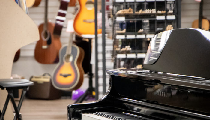 Yamaha Clavinova digital piano with guitars on wall behind it.