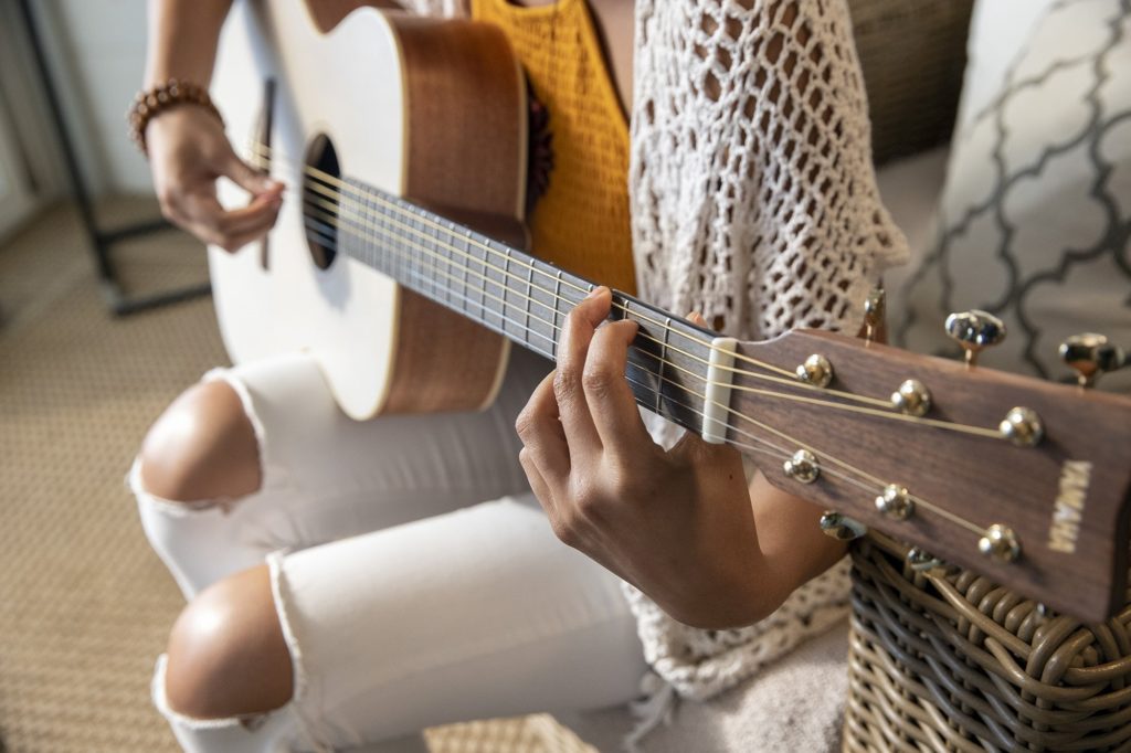 Close up of girls hands playing a yamaha storia guitar.