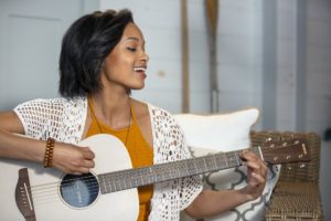 Girl singing while she plays guitar.