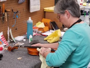 Woman cleaning violin and removing rosin after playing her instrument