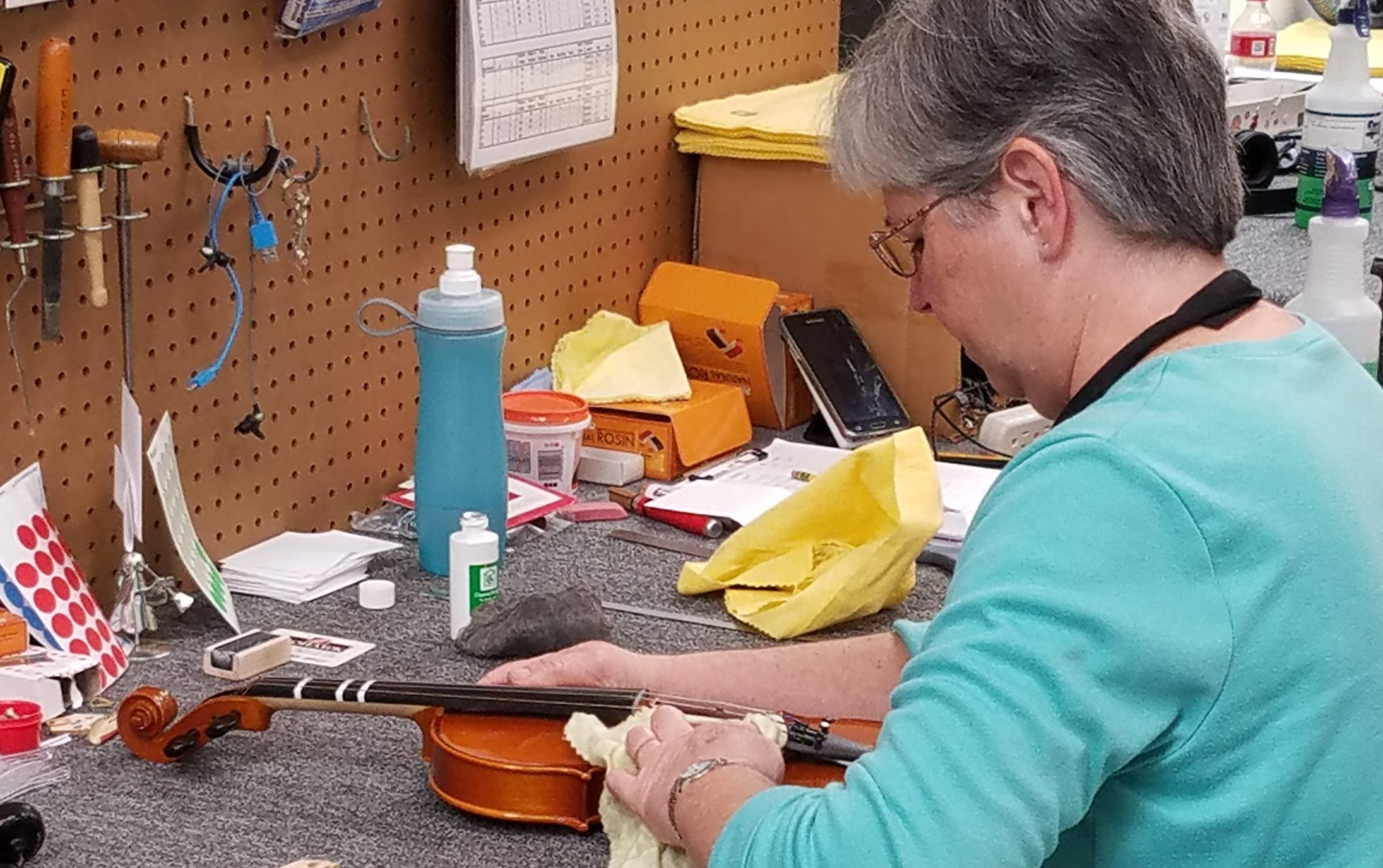 Woman cleaning violin and removing rosin after playing her instrument