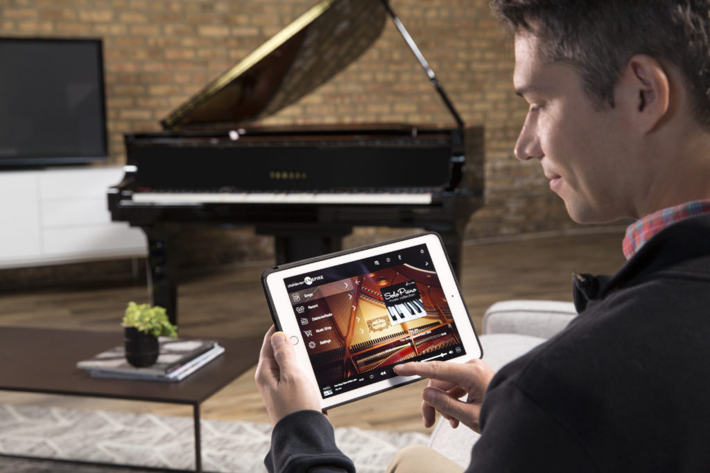 Man using Ipad to operate Yamaha Disklavier piano