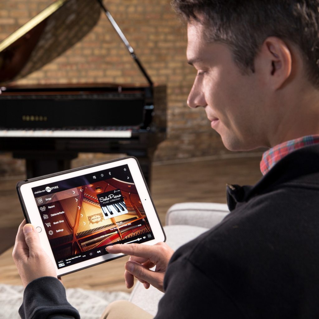 Man using Ipad to operate Yamaha Disklavier piano