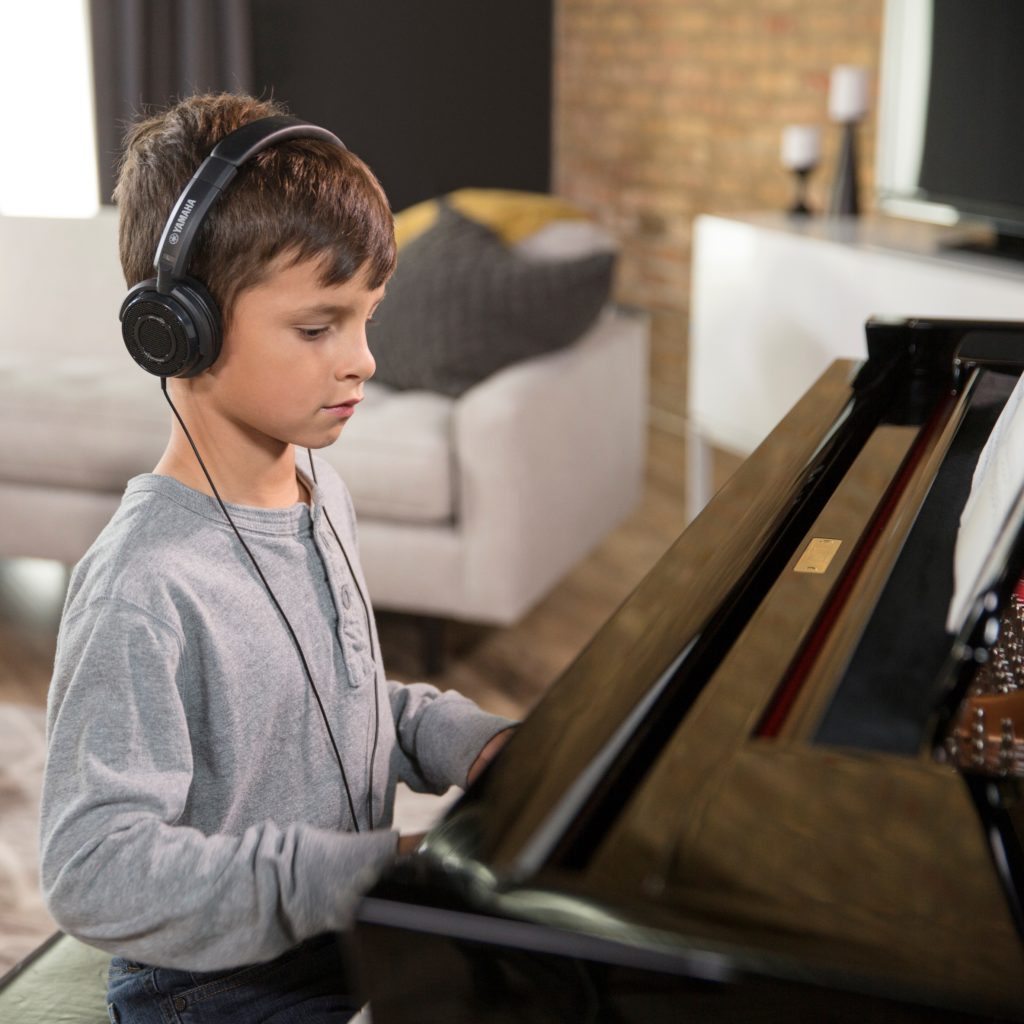 child with headphones playing piano