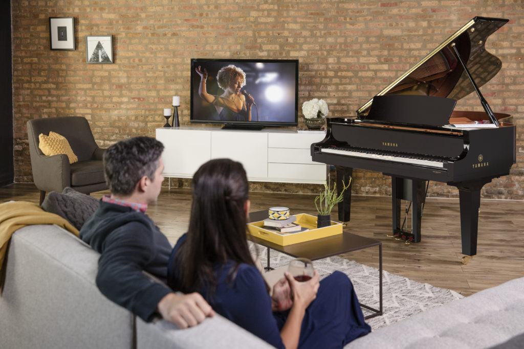 couple sitting on couch watching Yamaha Disklavier TV