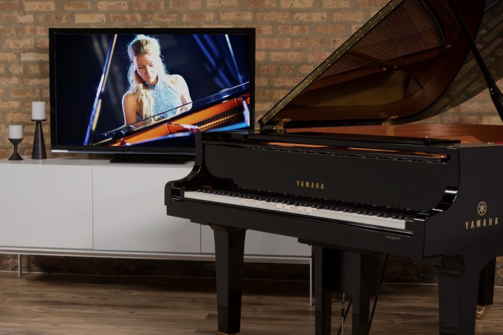 Yamaha Disklavier grand piano in front of brick wall