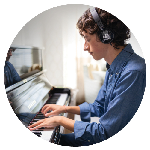 Teenage boy playing a Yamaha SILENT Piano™ with headphones.