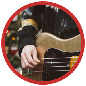 Closeup of a person's hand strumming a gold electric bass.
