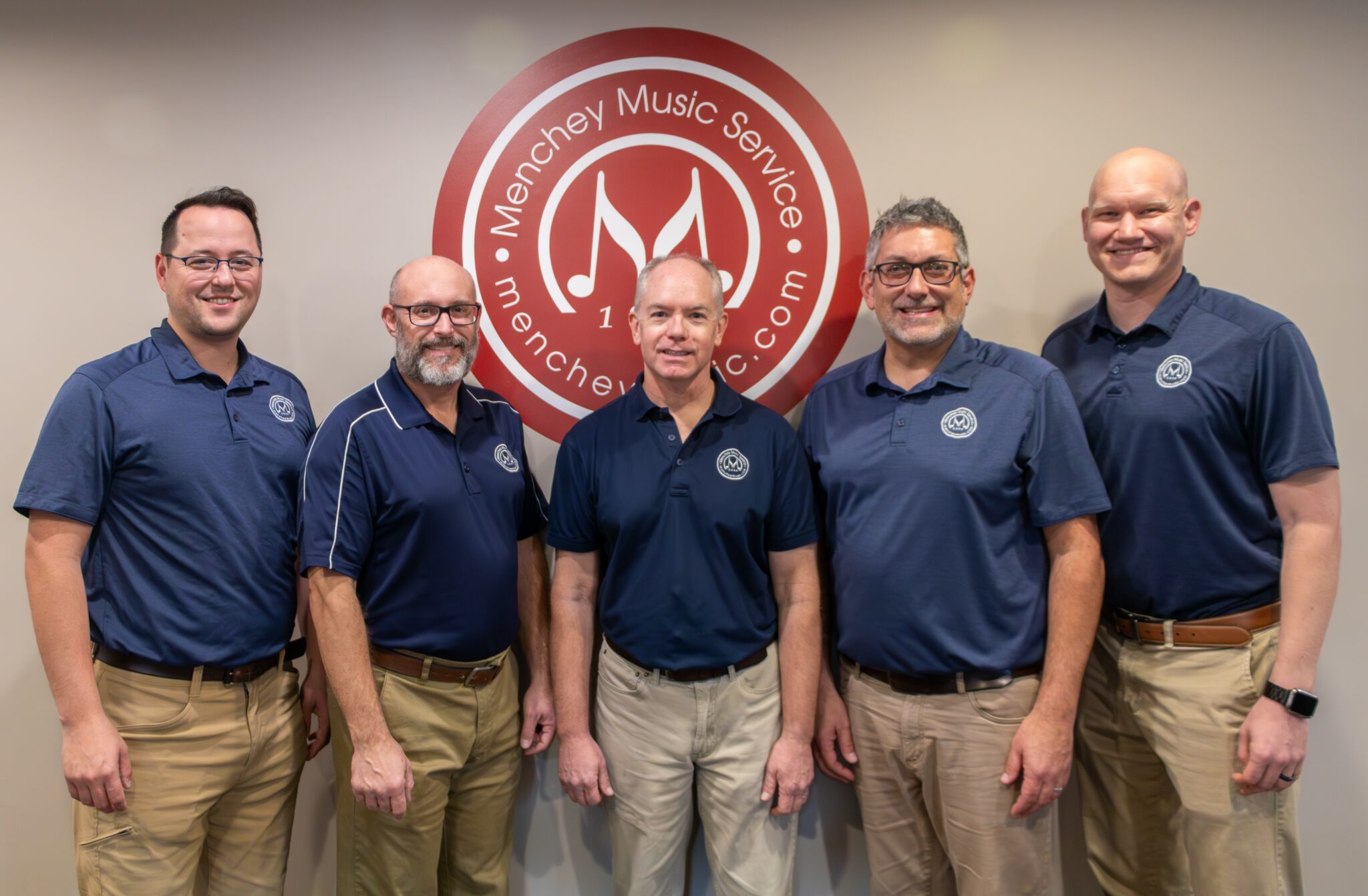 Photo of our education reps in front of Menchey Music logo.