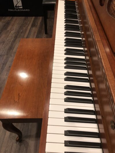 Up close view of the keys on a Yamaha M405 cherry upright, along with matching bench.