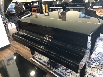 Fully closed view of a Kawai GE1 Polished ebony 5’1” baby grand (1612734) with matching bench.