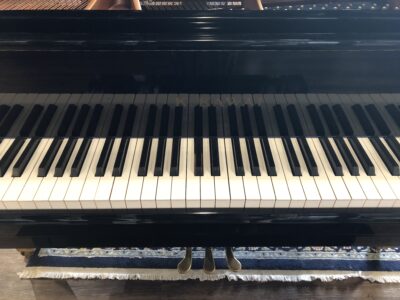 Keys and front logo of a Kawai GE1 Polished ebony 5’1” baby grand (1612734)