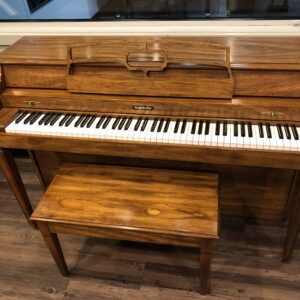 The front view of a Baldwin, model 1024, #1376388 pecan upright with matching bench.