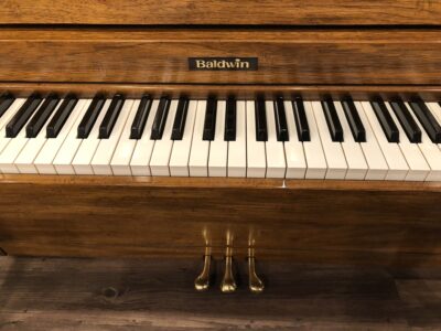 The front logo and pedals for the Baldwin, model 1024, #1376388 pecan upright.