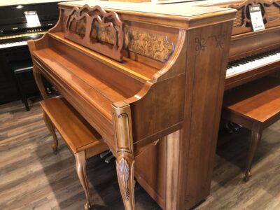 The side view of a closed fallboard of the Yamaha, Model M500P in cherry, #233143 from 1998 with matching bench.