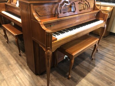 The closed fallboard on a Yamaha, Model M500P in cherry, #233143 from 1998 with matching bench.
