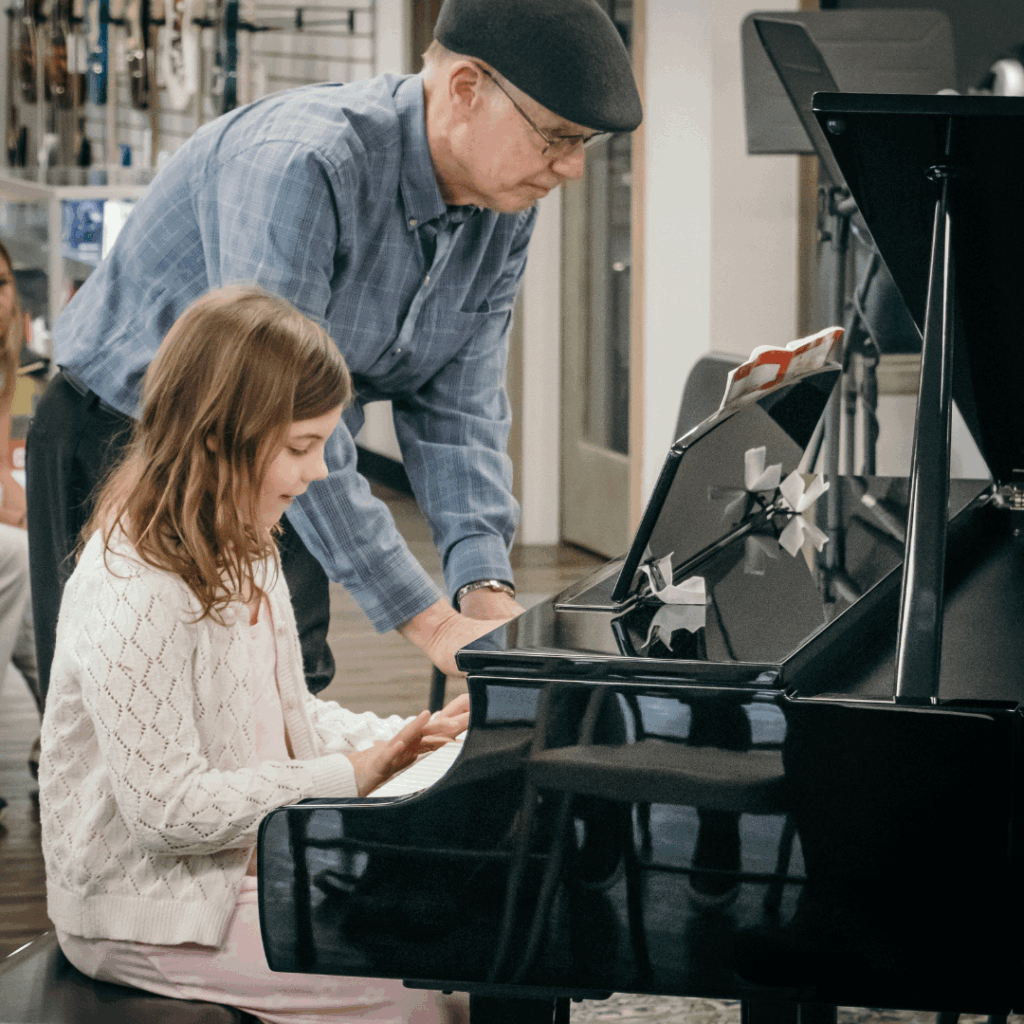A young student and a senior music teacher playing on the same piano. Demonstrates the lifelong impact of playing music.