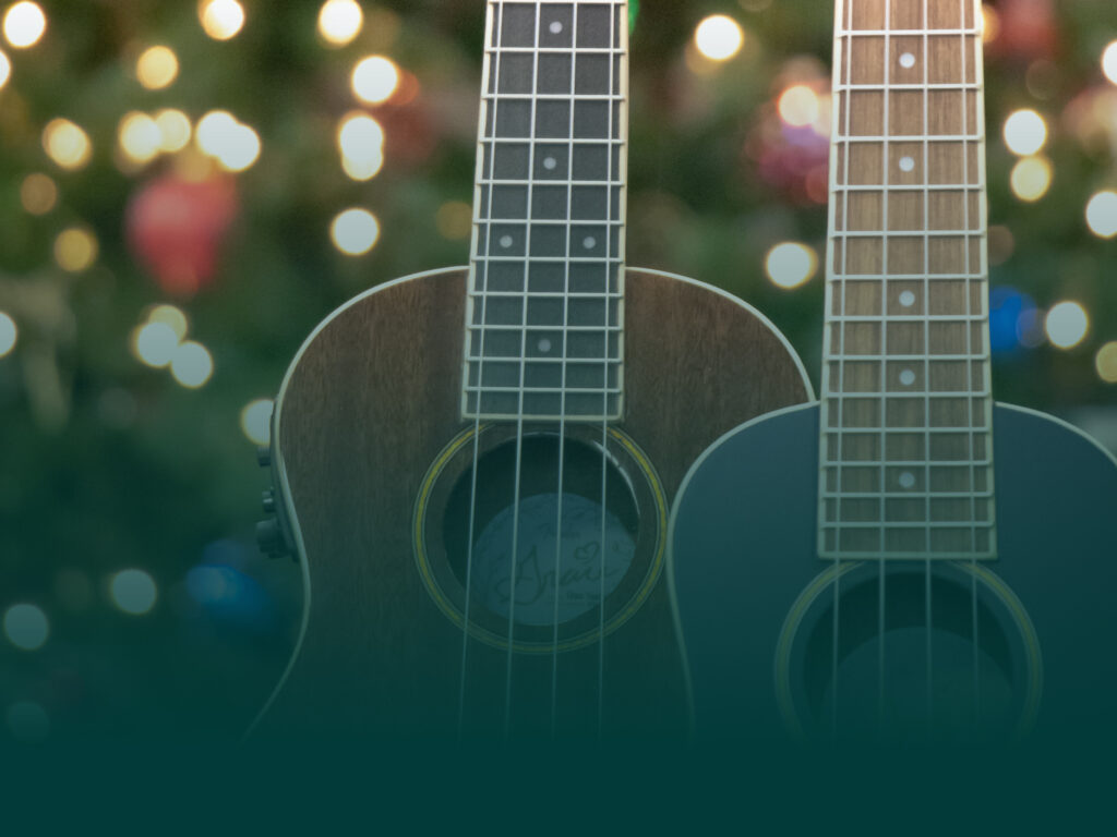 Background image of ukuleles in front of holiday lights.